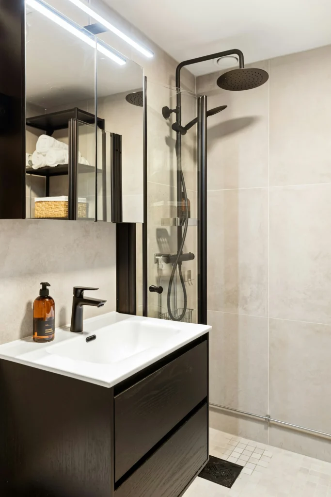Real photograph of a tiled bathroom with a shower, basin and mirror