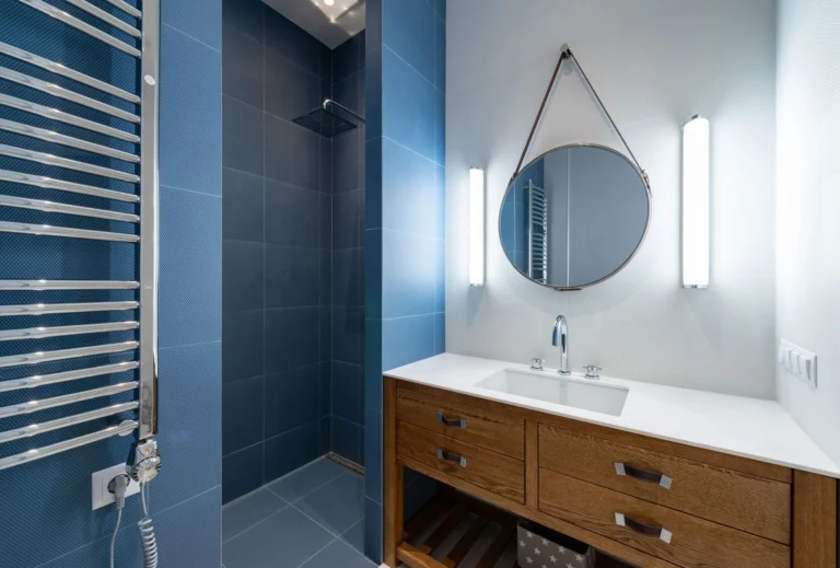 Blue tiled shower with timber vanity and round mirror